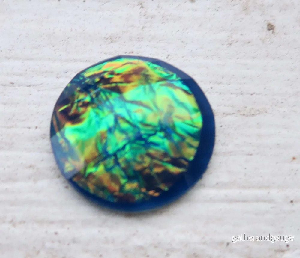 Cabochon av resin – Rund blå med oljeskimmer 15mm 1 styck Cabochon av resin – Rund blå med oljeskimmer 15mm 1 styck